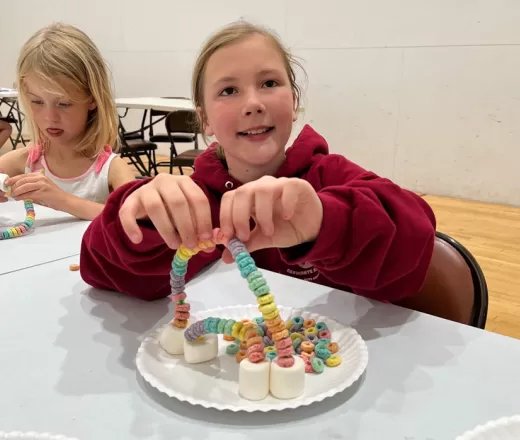 Two girls making a rainbow out of fruit loops and marsh mellows